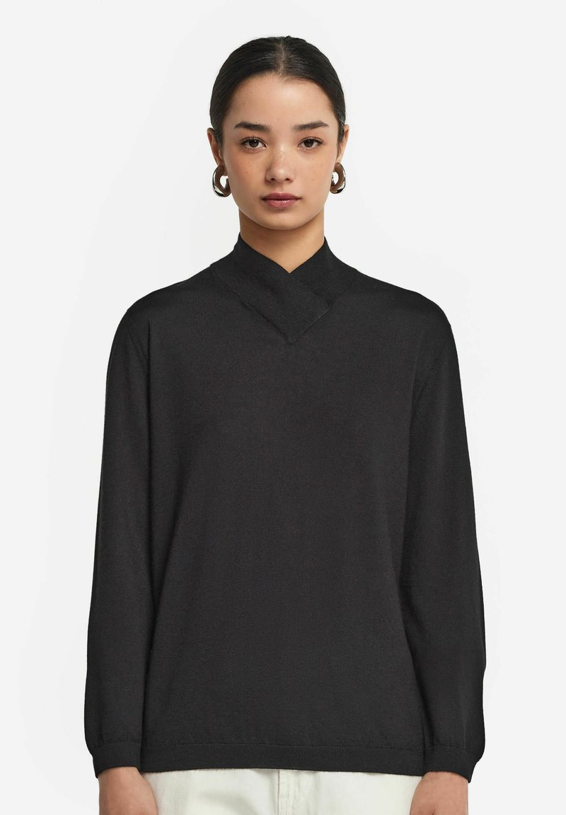 Schwarzer Pullover mit hohem Kragen und langen Ärmeln. Weiche Textur, leicht lockere Passform und minimalistisches Design ohne sichtbare Muster oder Beschläge.