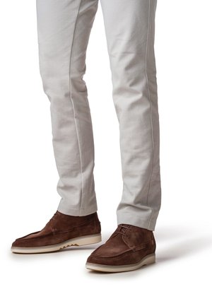 Braune Wildlederschuhe mit runder Spitze und dekorativen Nähten, kombiniert mit hellgrauen, maßgeschneiderten Hosen mit schmaler Passform und dezentem Seitensaum.