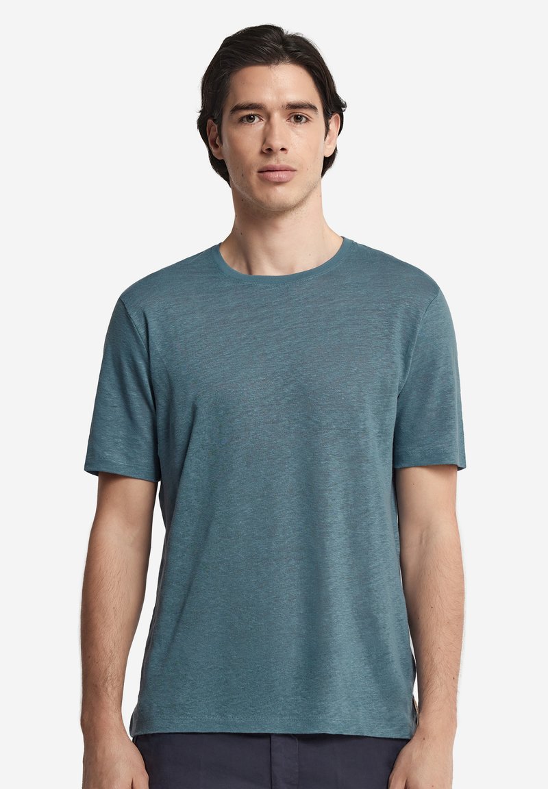 Kortärmad teal t-shirt tillverkad av ett lätt tyg med rundad halsringning och subtilt texturerad yta, figurnära men avslappnad passform.