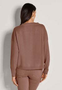 Brauner Oversize-Pullover mit Strickstruktur, gerippten Bündchen und Saum. Verfügt über ein sauberes Rückendesign mit minimalen Nähten und überschnittenen Schultern.