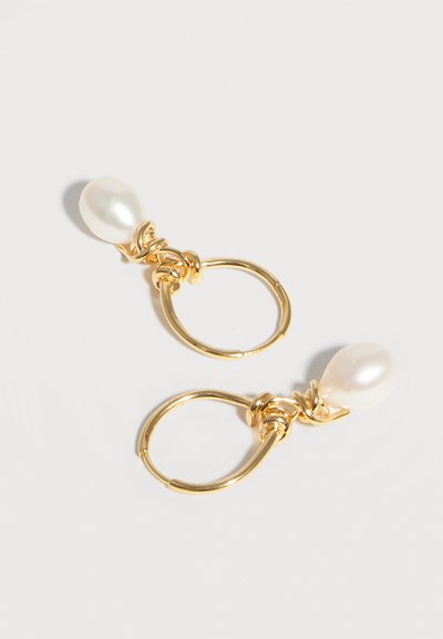 Χρυσά σκουλαρίκια κρίκοι με λευκά μαργαριτάρια σε σχήμα σταγονίδας, συνδεδεμένα με στριφτό χρυσό σύρμα σε λευκό φόντο.