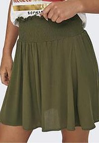 Jupe vert olive en tissu léger, avec une taille froncée et un design fluide et plissé. Texture douce, longueur genoux.