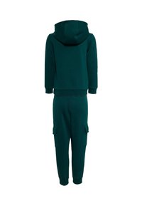Haut à capuche en coton vert et joggers assortis. Le haut à capuche dispose d'une grande capuche ; les joggers ont des poches cargo et des poignets ajustés aux chevilles.