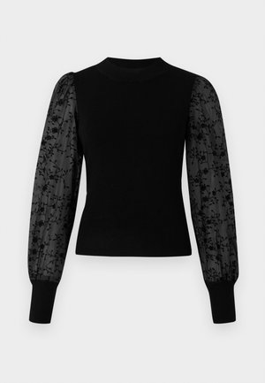 Černý žebrovaný svetr s průsvitnými černými nafouknutými rukávy s květinovým vzorem. Má vysoký výstřih a přiléhavé manžety na koncích rukávů.