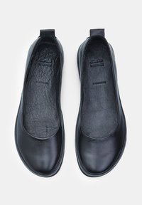 Bailarinas de cuero negro con una textura suave, punta redondeada y un diseño minimalista. Cuentan con un pequeño tacón y un forro interior suave.