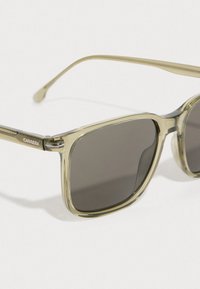 Gafas de sol cuadradas de color verde con lentes gris oscuro, marco de plástico ligero y detalles metálicos, con un logotipo en la patilla.