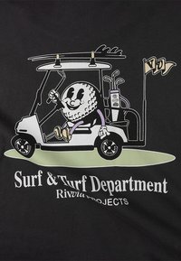 Camiseta gráfica con un personaje de bola de golf caricaturesca conduciendo un carrito de golf, con el texto "Surf & Turf Department" en blanco sobre un fondo negro.