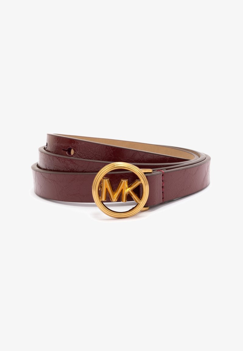 Ceinture en cuir bordeaux foncé enroulée avec une boucle circulaire dorée brillante présentant un logo MK en relief au centre, sur fond blanc.