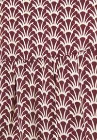 Fabric with a repeating maroon and white fan pattern, featuring crisp lines and a slightly textured surface. Includes gathered pleats along the seam.