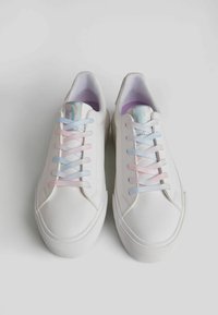 White sneakers with smooth leather and textured rubber soles. Features pink and blue laces, with a soft purple interior.