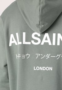 Green hoodie with a textured fabric featuring white text that reads "ALLSAINTS," Japanese characters, and "LONDON" on the back.