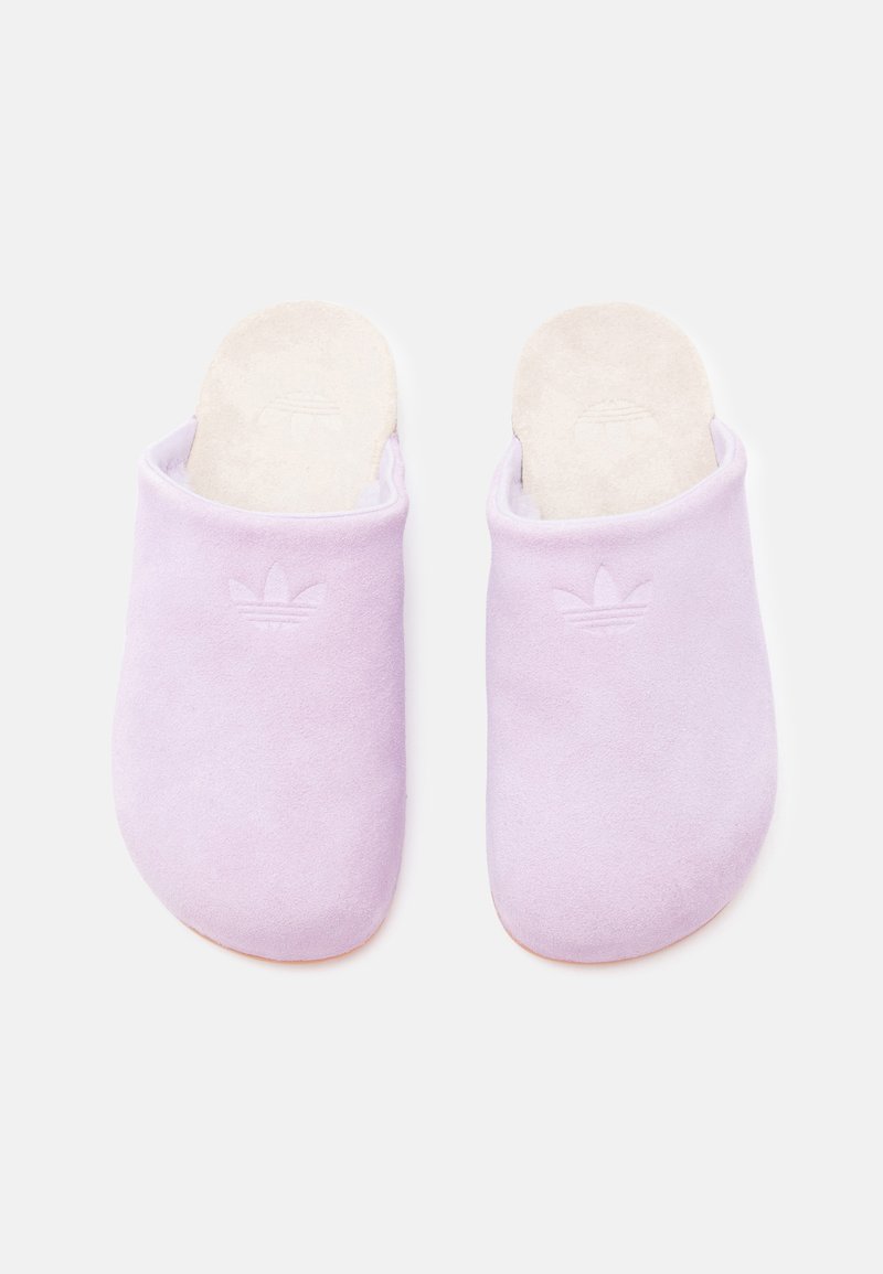 Lilac suede slip-on slippers with a soft textured surface and a white cushioned insole. Features embossed logo on the front.