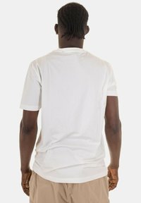 T-shirt bianco in cotone con scollo rotondo e maniche corte, texture liscia e vestibilità rilassata, visto da dietro.