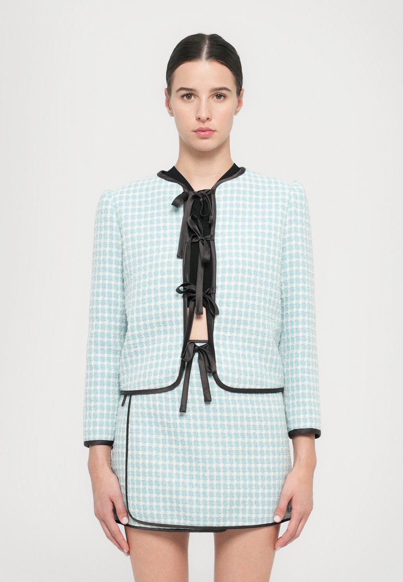 Sacou cu carouri de culoare bleu deschis, cu detalii negre și cravată, asortat cu o fustă similară. Material texturat, design ajustat și mâneci până la trei sferturi.