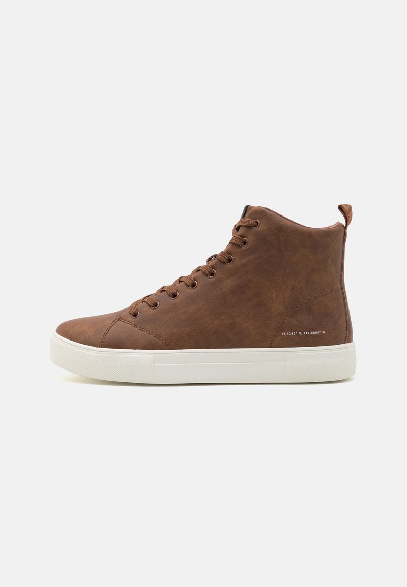 Brune lær høye sneakers med hvit gummisåle, rund tå og metalløyler, med en liten trekkflik bak.