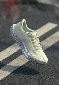 Αθλητικό παπούτσι ανοιχτού πράσινου χρώματος με επάνω μέρος από διχτυωτό υλικό, κλείσιμο με κορδόνι και λευκή σόλα. Διαθέτει κομψό σχέδιο και χαρακτηριστική λογότυπη λεπτομέρεια.