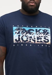 Marineblå bomulds T-shirt med grafisk tryk af palmer og en skyline, med teksten "Authentic Jack & Jones" og en afslappet pasform.