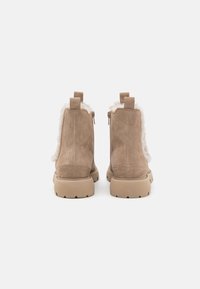 Botas de tobillo de ante color tostado con un forro de piel de textura suave, cremalleras laterales y una suela de goma. Incluye lengüetas en la parte posterior para facilitar el uso.