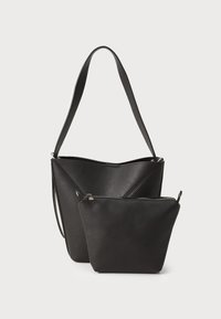 Melna ādas somiņa ar platu siksnu un izteiksmīgu leņķveida formu, kurai ir neliela kabata ar rāvējslēdzēju, izgatavota no tāda paša materiāla un krāsas.