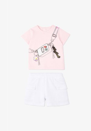 T-shirt rose clair à manches courtes avec sac bandoulière imprimé et short blanc à taille élastique avec poches à rabat, posé à plat sur fond blanc.