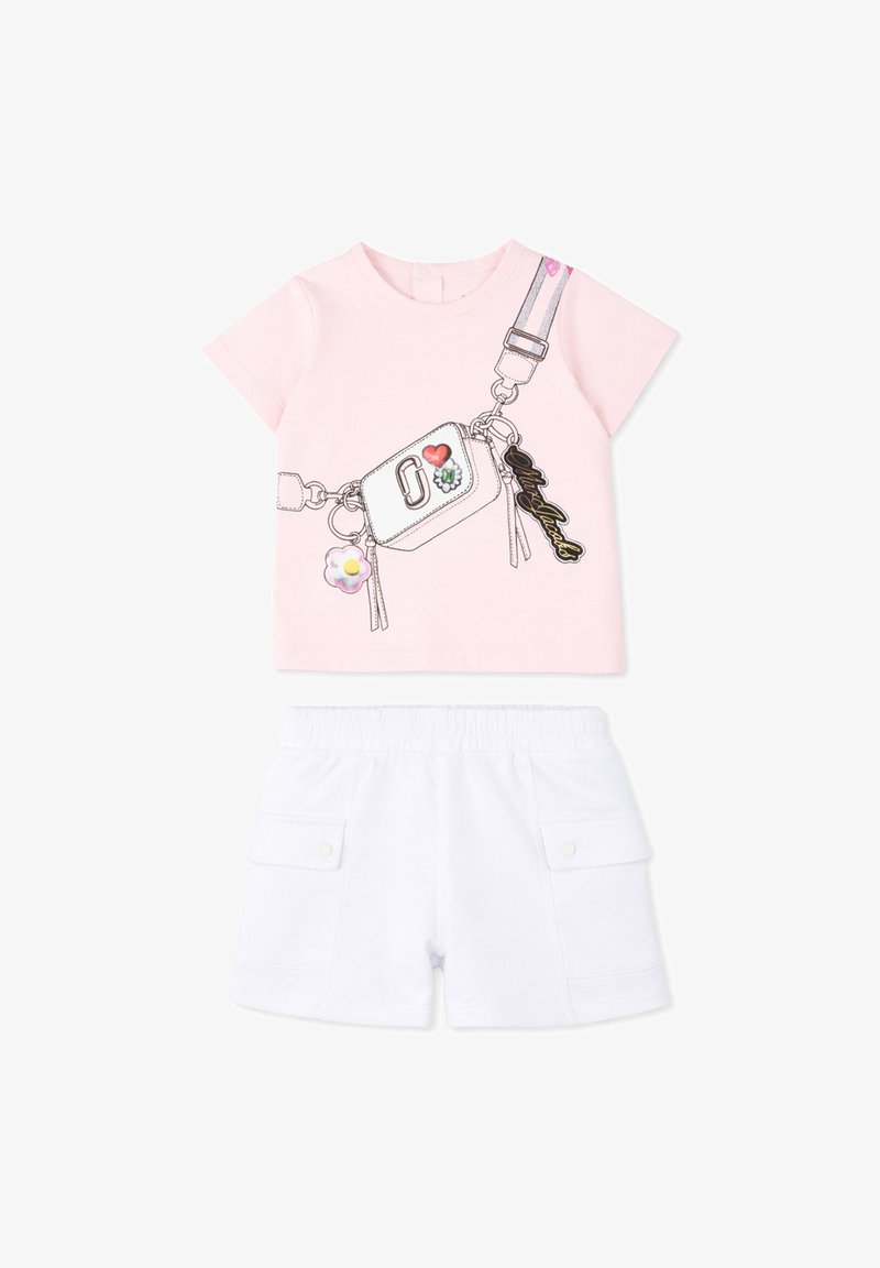 T-shirt rose clair à manches courtes avec sac bandoulière imprimé et short blanc à taille élastique avec poches à rabat, posé à plat sur fond blanc.