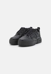 Black leather sneakers with a chunky sole, featuring lace-up design, textured accents, and logo detail. Smooth surface and padded collar.