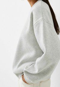 Gray sweatshirt with long sleeves and ribbed cuffs. Soft cotton blend fabric, relaxed fit, rounded neckline, and side hand pockets.