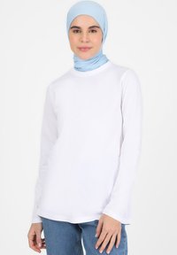 Weißes Langarmoberteil mit Rundhalsausschnitt, gefertigt aus glattem Stoff; kombiniert mit einem hellblauen, figurbetonten Hijab. Einfaches, klassisches Design.