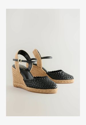 Fekete fonott bőr magassarkú szandál, jutas borítású talppal, állítható bokapánttal és texturált felülettel a lábujj résznél.