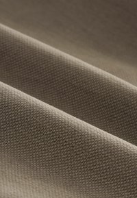 Raksturīga brūna auduma tekstūra ar smalku austu rakstu, kas parāda krokas un ēnas dziļumam. Gluda un maiga tekstūra.