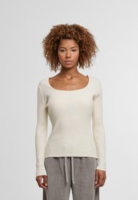 Cremfarbener, gerippter Langarmpullover mit einem quadratischen Ausschnitt. Weicher Stoff, taillierte Passform und sanfter Stretch ergänzen einen lässigen Stil.