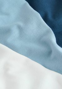 Textília s tromi vodorovnými farebnými pásmi: tmavomodrá, svetlomodrá a biela. Tkanina je mäkká, hladká a mierne textúrovaná.