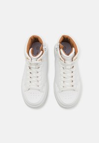 Białe wysokie sneakersy z gładkiej skórzanej powierzchni, sznurowanym fasonem, wyściełanym kołnierzem, brązowym wnętrzem i drobnymi perforacjami na palcach.