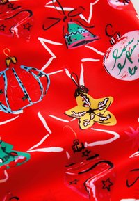 Tessuto rosso con finitura lucida che presenta vari ornamenti natalizi colorati, tra cui stelle, campane e palline con design giocosi.