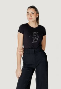 T-shirt nera a maniche corte con scollatura rotonda e design del logo metallico. Abbinato a pantaloni neri a vita alta. Texture del tessuto liscia.
