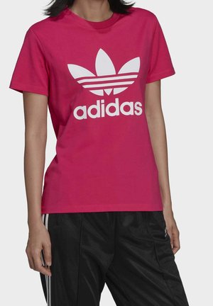 Pink cotton T-shirt featuring a large white Adidas logo and three stripes in the design. Short sleeves and a classic crew neck style.