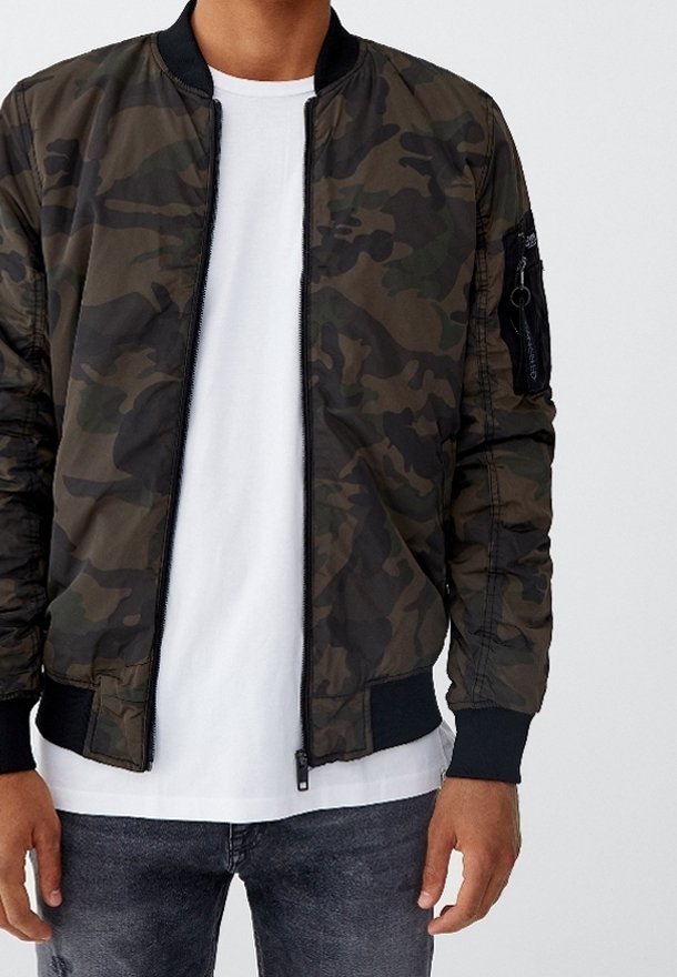 Veste bomber camouflage en vert foncé et noir, dotée d'une fermeture éclair frontale, de poignets côtelés et d'une poche zippée sur la manche.