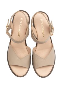 Beżowe skórzane sandały z V-kształtnym wzorem paska, z regulowanym zapięciem na kostce i płaską brązową podeszwą. Wewnętrzna strona z wytłoczonym logo marki.