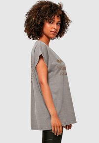 Grå oversized t-shirt med korte ærmer og rund hals. Har et subtilt grafisk design i en kontrastfarve på forsiden.