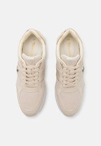 Baskets beiges avec une tige texturée et pailletée. Elles possèdent des lacets crème, un col rembourré, et une semelle en caoutchouc blanche. Taille 37.