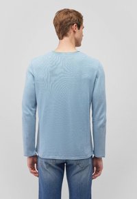 Helles blaues Langarmshirt mit Rundhalsausschnitt und gerippter Textur. Verfügt über einen geraden Schnitt und kontrastierende Nähte entlang des Saums.