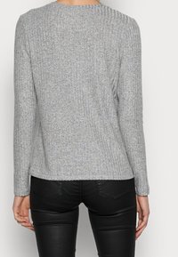 Grå randig tröja med långa ärmar, rund halsringning och ett texturerat, mjukt tyg. Baksidan har en något utsvängd silhuett.