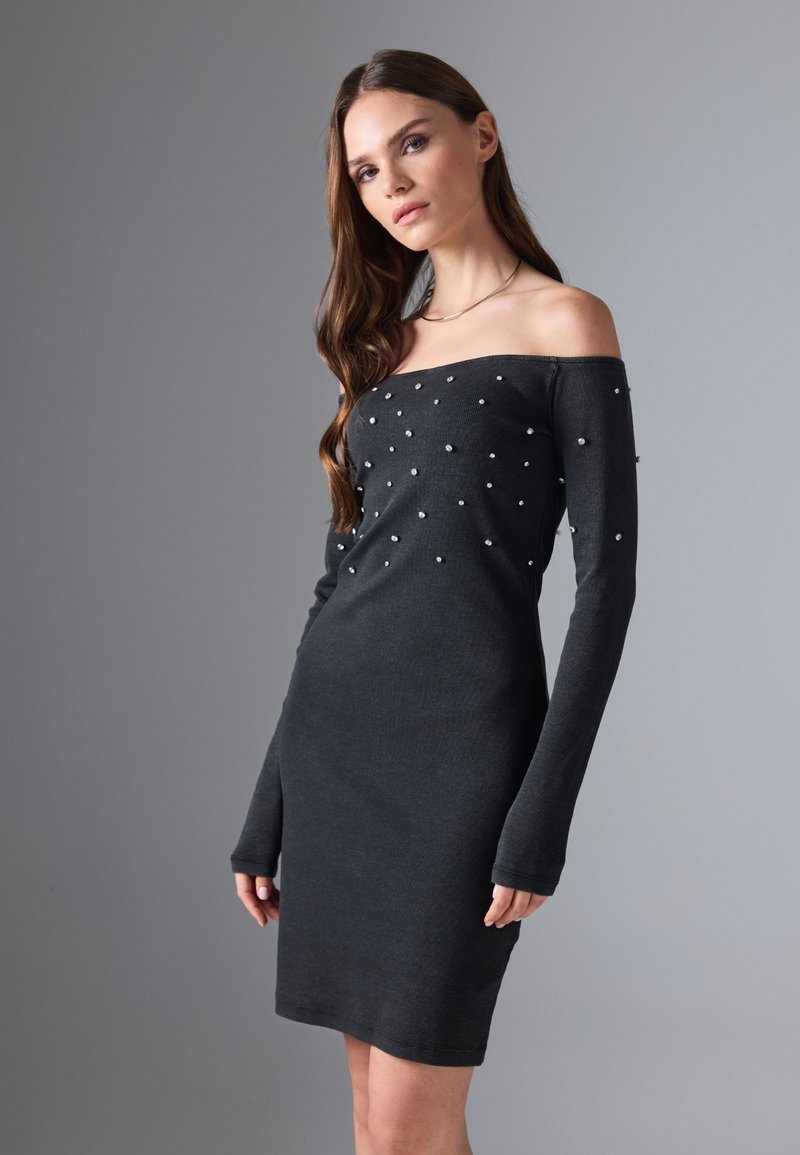 Schwarzes, geripptes Off-Shoulder-Kleid mit langen Ärmeln, das auf der Vorderseite verstreute Perlenakzente aufweist. Figurbetonte Silhouette, knielang.