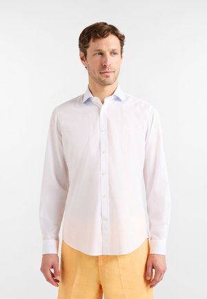 Camicia bianca con bottoni, colletto azzurro chiaro, maniche lunghe e orlo curvo. Presenta un piccolo logo sul lato sinistro.