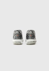 Running shoes with a mesh upper in black and grey, featuring a white sole and red accents. Low-profile design with padded collar.