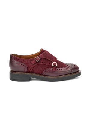 Scarpa in pelle bordeaux e suede con dettagli brogue, due fascette con fibbie, punta arrotondata e suola in gomma nera. Finitura liscia e strutturata.