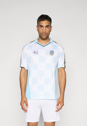 Lichtblauw voetbalshirt met een geruit patroon, zwarte accenten, kraag en Champion-logo. Draagt samen met witte shorts. Korte mouwen.