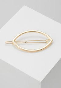 Auksinės spalvos plaukų segtukas, kuriam suteikta pailga ovališka forma, su lygiu, poliruotu paviršiumi ir paprastu segtuku, skirtu plaukams pritvirtinti.