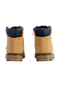 Bottines en cuir marron avec un col rembourré noir et une fermeture éclair, présentant une semelle en caoutchouc texturée et le logo "Levi's" à l'arrière.