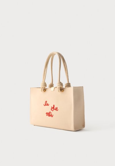 Μπεζ ορθογώνια τσάντα tote με παχιά στριφτά σχοινιά ως χερούλια και κόκκινο γραφικό κείμενο "la dolce vita" μπροστά.